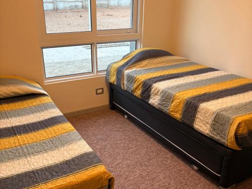 een slaapkamer met twee bedden en een raam bij Comodo y cercano a la playa in Coquimbo
