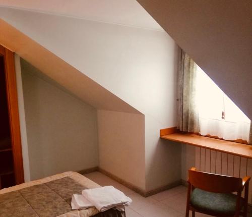 Cette chambre comprend un lit, une fenêtre et une chaise. dans l'établissement Hostal Libertad, à Villadangos del Páramo