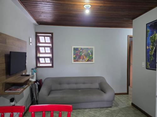 een woonkamer met een bank en 2 rode stoelen bij Armação - Florianópolis - 2 quartos de casal in Florianópolis