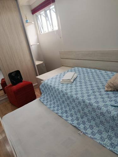 a bedroom with a bed with a blue blanket and a red chair at Doce aconchego in Pato Branco