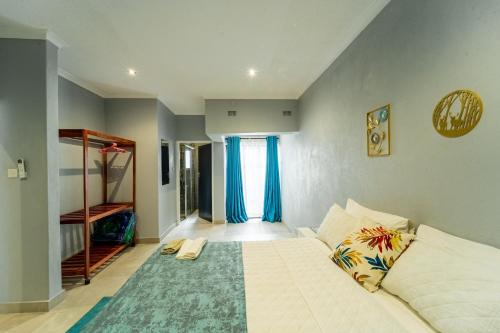 una camera da letto con un grande letto bianco con tende blu di KhayaLethu Vic Falls 2 a Victoria Falls