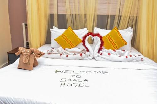 a white bed with yellow and red pillows on it at `Saala Hotel Limited in Isiolo