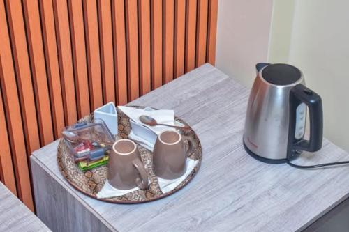 a table with a tea kettle and mugs on it at `Saala Hotel Limited in Isiolo