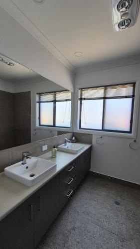 a bathroom with two sinks and a large mirror at Silverwoods 17th Hole Retreat in Yarrawonga