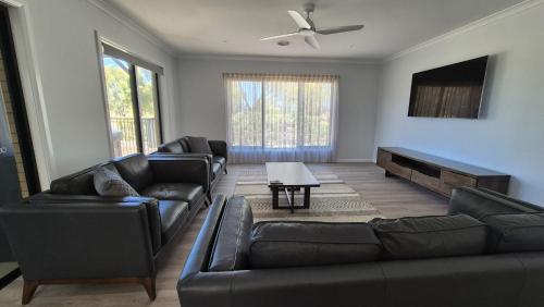 a living room with two leather couches and a tv at Silverwoods 17th Hole Retreat in Yarrawonga