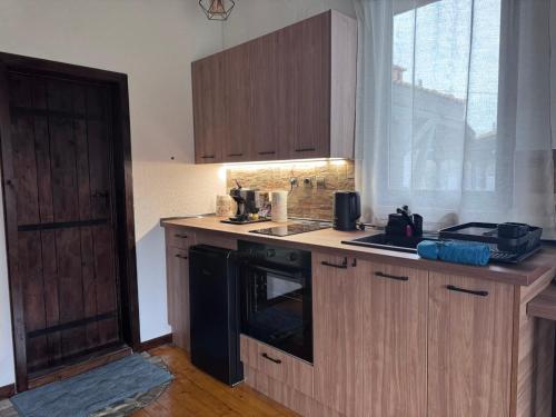 eine Küche mit Holzschränken und einem Backofen mit schwarzem Kochfeld in der Unterkunft RhodoNest in Kara Agach