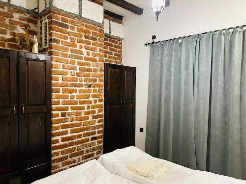a bedroom with a bed and a brick wall at RhodoNest in Kara Agach