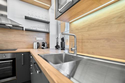 een keuken met een roestvrijstalen wastafel en houten kasten bij George 01 by Mountain ways in Kovářská