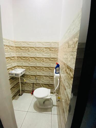 a bathroom with a toilet and a sink at Dh Hotel in Bhiwāni