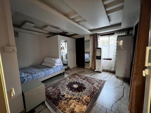 une chambre avec un lit et un tapis au sol dans l'établissement Triluna Apartments, à Pātan