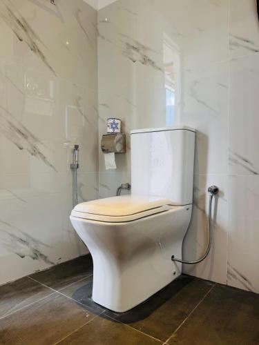 a white toilet in a bathroom with marble walls at Rainforest cabin in Deniyaya