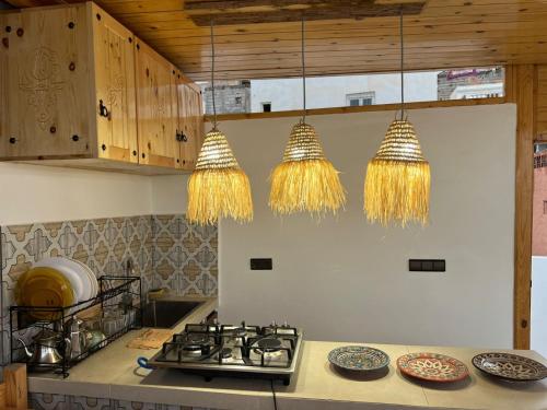 een keuken met een fornuis en een paar kroonluchters bij tawja surf house in Taghazout