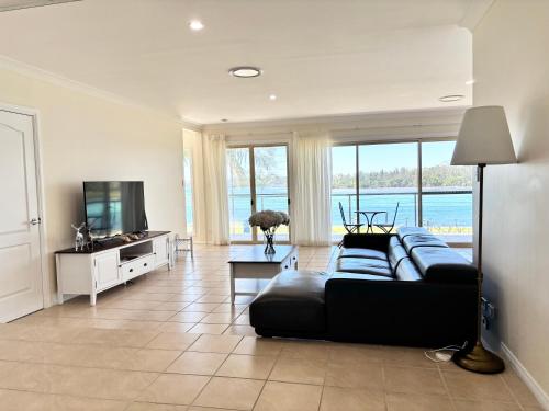 a living room with a black couch and a television at Riviera Caravan Park in Sussex inlet