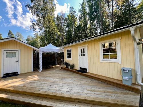 une maison avec une terrasse et une tente dans l'établissement Karamellgårdens stuga, à Herräng