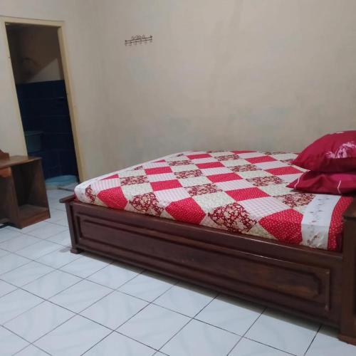 a bedroom with a bed with a red and white quilt at Baron Sari Homestay in Pulau Kukup