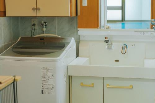 a kitchen with a sink and a washing machine at Nagoya in Nakijin