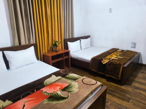 een hotelkamer met twee bedden en een tafel bij Glenfall Guest in Nuwara Eliya