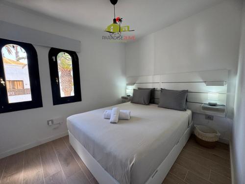 a bedroom with a white bed with two towels on it at Casa Dudu in Corralejo