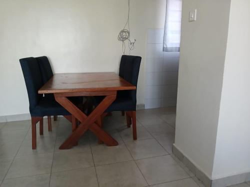 a wooden table and two chairs sitting next to a wall at Beijing Nest in Syokimau