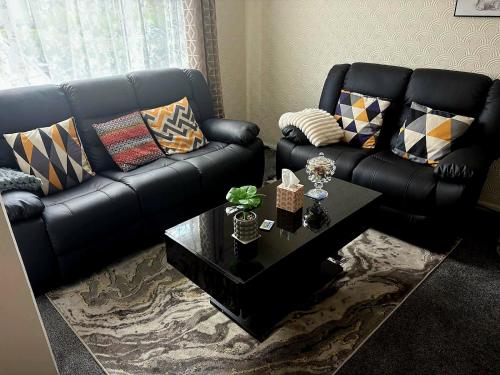een woonkamer met een zwarte leren bank en een tafel bij High class accommodations 10 in Little Hulton