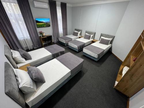 een hotelkamer met drie bedden en twee stoelen bij Kesh Hotel in Tasjkent