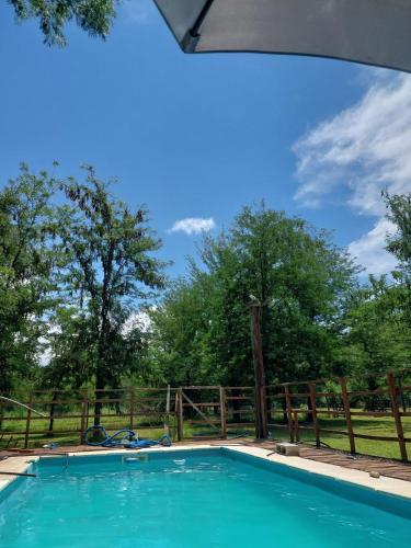 une piscine avec une clôture et des arbres dans l'établissement Canaña Los Comechingones, à Santa Rosa de Calamuchita