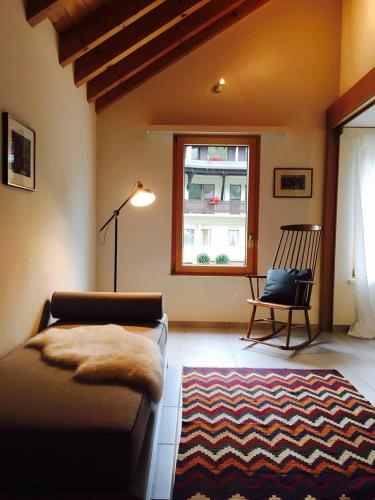 a living room with a couch and a chair and a window at Ferienhaus Grüner Heinrich in Andermatt