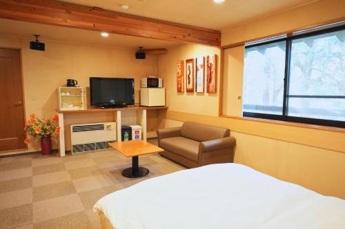 a bedroom with a bed and a tv and a chair at Parco山荘 in Ito