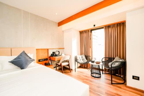 a hotel room with a bed and a desk and chairs at Nestlay Suites by TC One in Kozhikode