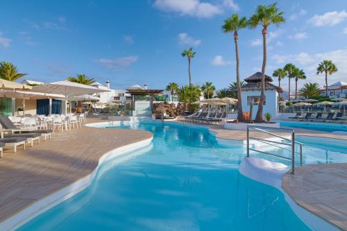 een zwembad op een resort met palmbomen bij Boutique Hotel H10 White Suites - Adults Only in Playa Blanca