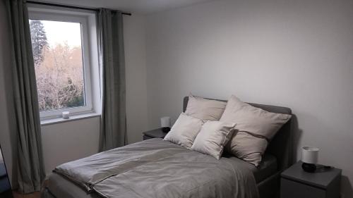een bed met kussens in een slaapkamer met een raam bij Apartment -Wohnung Herford in Herford