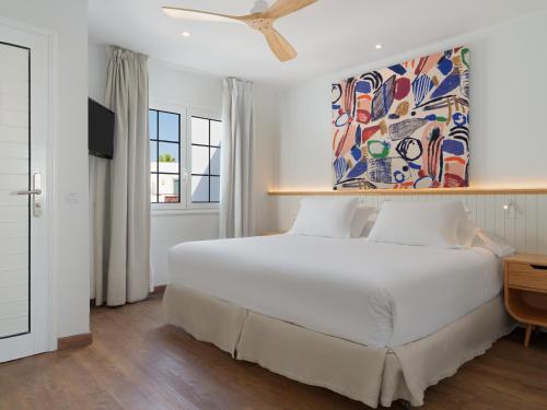 a bedroom with a large white bed with a painting on the wall at Boutique Hotel H10 White Suites - Adults Only in Playa Blanca