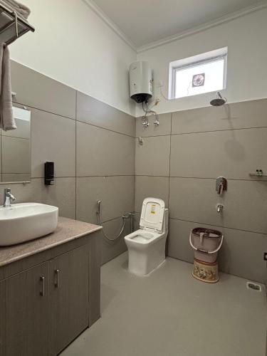 a bathroom with a toilet and a sink and a window at Pacific Inn Vistaar Hotels & Resorts in Chamba