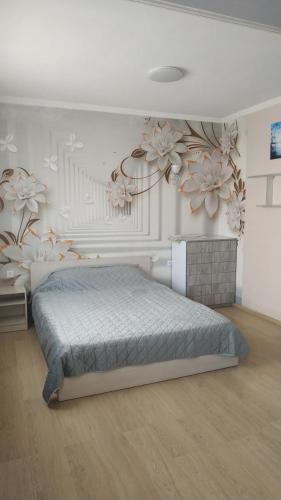 a bedroom with a bed and flowers on the wall at Современная студия-люкс, слобожанській in Samarovka