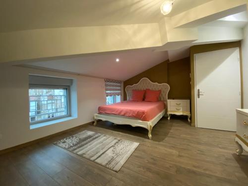 ein Schlafzimmer mit einem Bett mit roten Laken und einem Fenster in der Unterkunft Le Savoyard in Saint Etienne