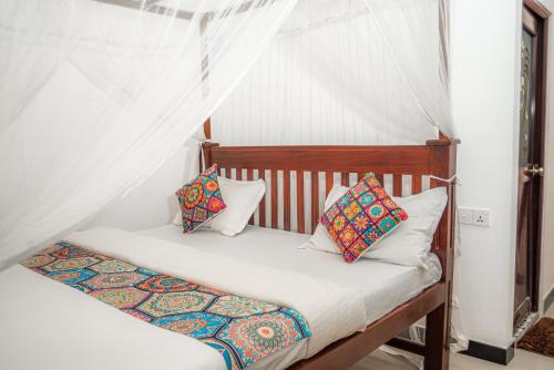 een slaapkamer met een hemelbed en kussens bij Villa Prime Time Unawatuna in Unawatuna