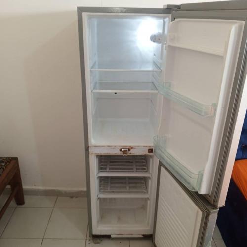 un réfrigérateur vide avec sa porte ouverte dans une cuisine dans l'établissement Chez Bernard, à Libreville