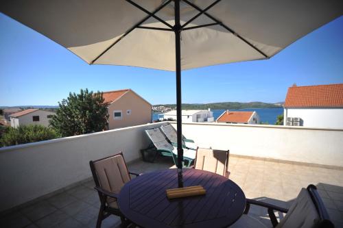 una mesa con sombrilla en el balcón en Villa Bianca, en Trogir