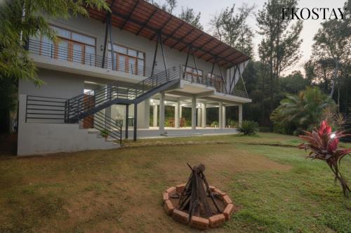 a house with a balcony and a large yard at EKOSTAY - Forest Cube Villa in Attigundi