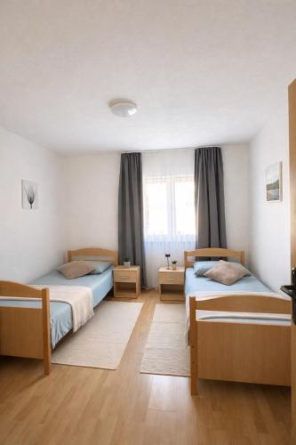 a bedroom with two beds and a window at Apartman Mila in Golubić