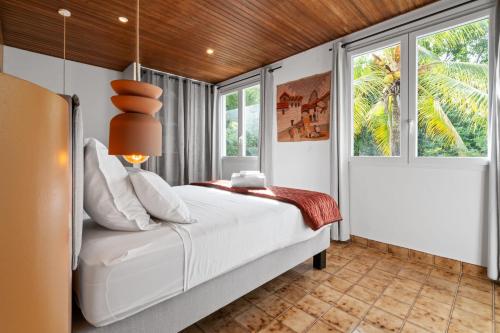 a bedroom with a white bed and windows at Villa Calaïa in Tartane