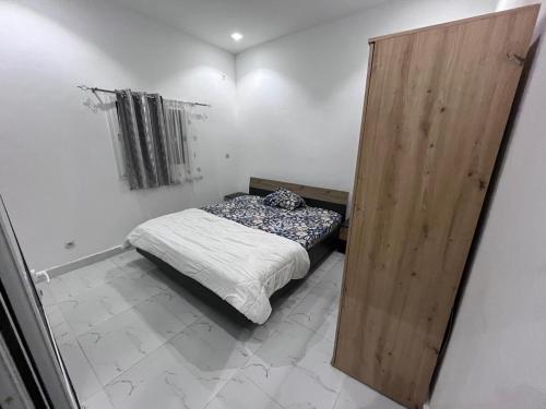 een kleine slaapkamer met een bed en een houten deur bij Teranga in Mbour