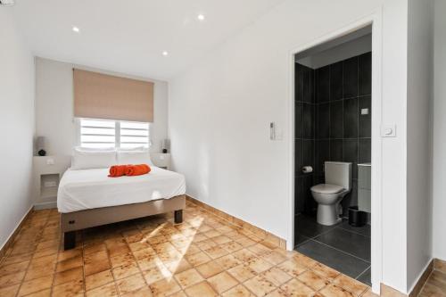 a white bedroom with a bed and a toilet at Villa Calaïa in Tartane
