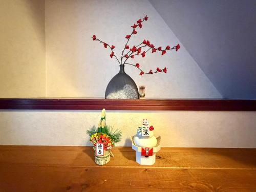 a shelf with a vase with a plant and a vase with a flower at Ninja Tokyo Hideaway Higashi-Shinkoiwa in Tokyo