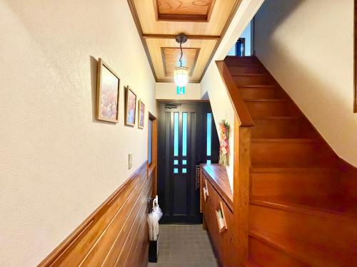 a hallway with wooden floors and a staircase with a black door at Ninja Tokyo Hideaway Higashi-Shinkoiwa in Tokyo