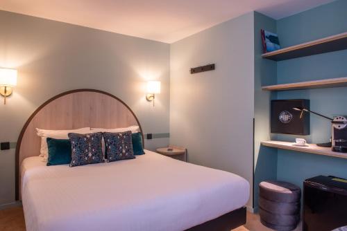 a bedroom with a white bed with a wooden headboard at Hotel France Albion in Paris