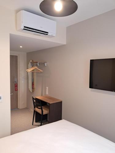 een kamer met een bureau, een tv en een stoel bij Hôtel du Cheval Blanc Brunstatt in Brunstatt