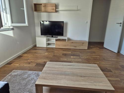 ein Wohnzimmer mit einem TV und Holzböden in der Unterkunft Flat near Serra da Arrábida, beaches and Lisbon in Quinta do Conde