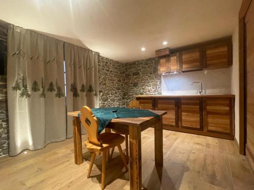 een keuken met een houten tafel met 2 stoelen bij Affittacamere L'Abri in Etroubles