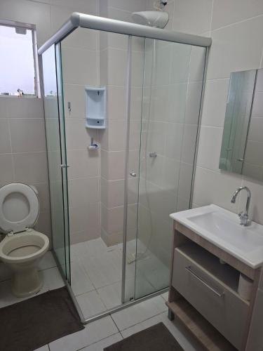 a bathroom with a shower and a toilet and a sink at Apart próximo a Unimed, Catedral e HSA com 2 quartos com 2 ARES e garagem in Santo Ângelo